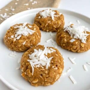 A plate of healthy no-bake coconut cookies, garnished with extra shredded coconut flakes.